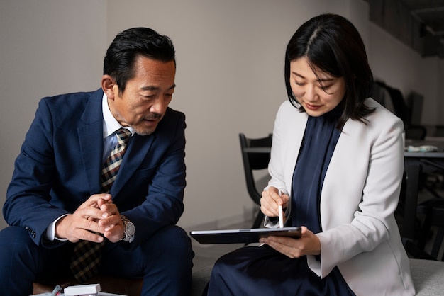 무료 사진 ipad로 작업하는 중간 샷 비즈니스 사람들