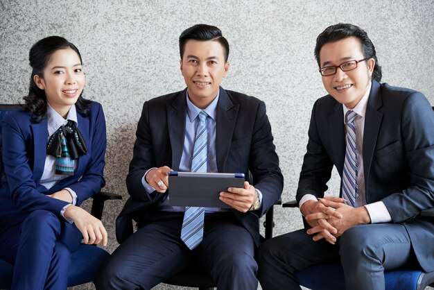Medium shot of a business team sitting in the office with tablet PC