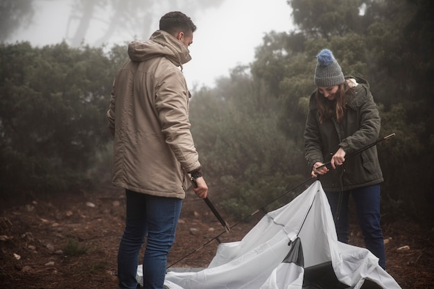 Free photo medium shot campers putting up a tent