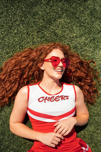 Foto gratuita cheerleader a tiro medio sdraiato sull'erba