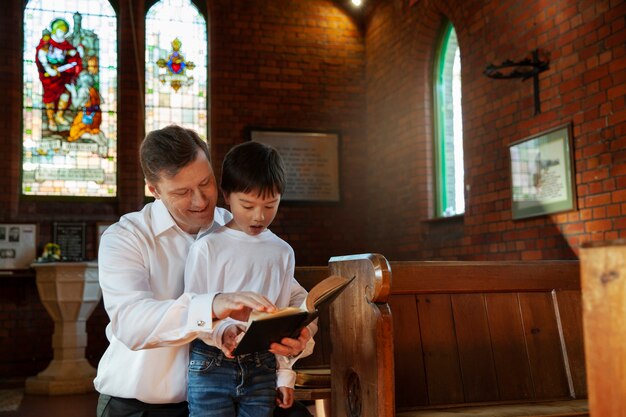 Medium shot christian kid and man reading bible