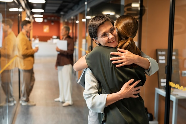 Free photo medium shot colleagues hugging at work