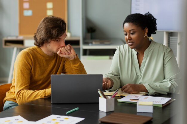 Medium shot colleagues sitting at desk