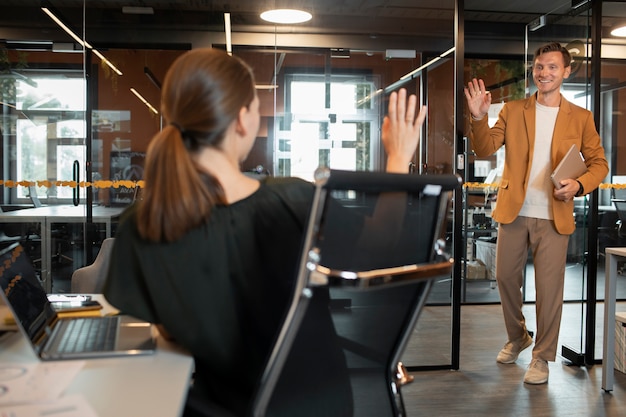 Free photo medium shot colleagues waving hands at each other