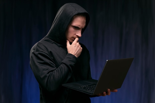 Hacker interessato a colpo medio che tiene in mano un laptop