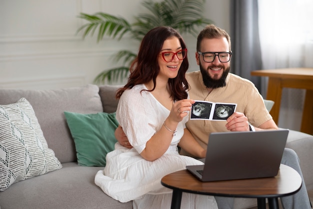 Foto gratuita coppia di tiro medio che annuncia la gravidanza con il computer portatile