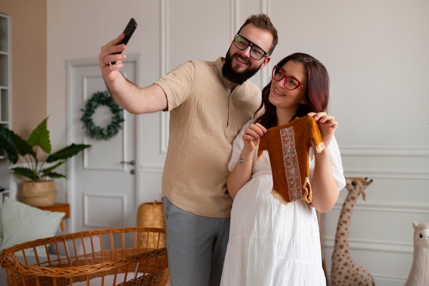 スマートフォンで妊娠を発表するミディアムショットのカップル