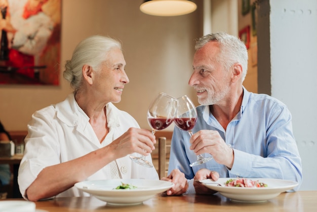 Medium shot couple clinking glasses in a toast