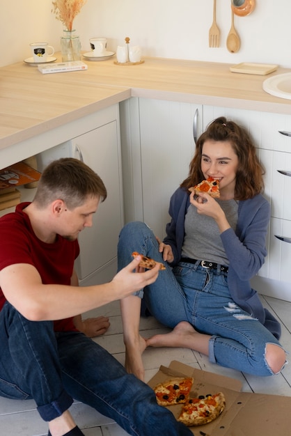 Medium shot couple eating pizza