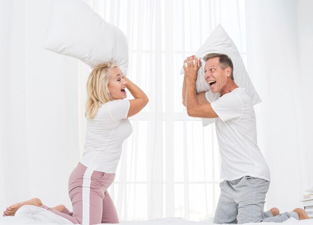 Medium shot couple having a pillow fight