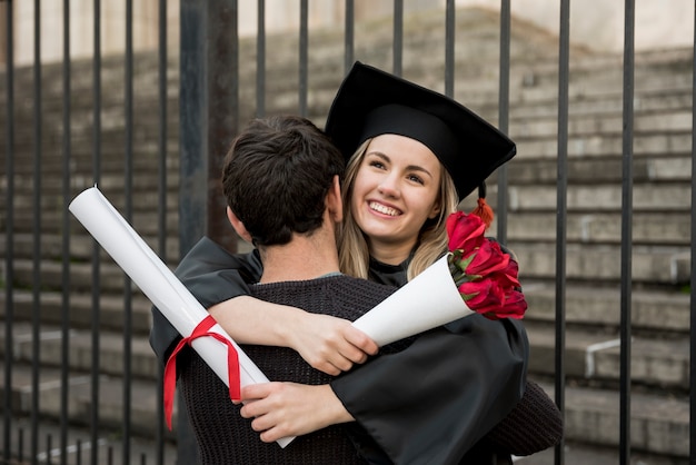 Free photo medium shot couple hugging at graduation