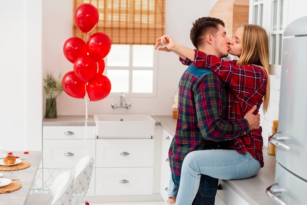 Medium shot couple kissing in the kitchen