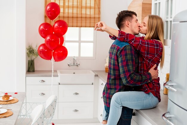 ミディアムショットのカップルが台所でキス