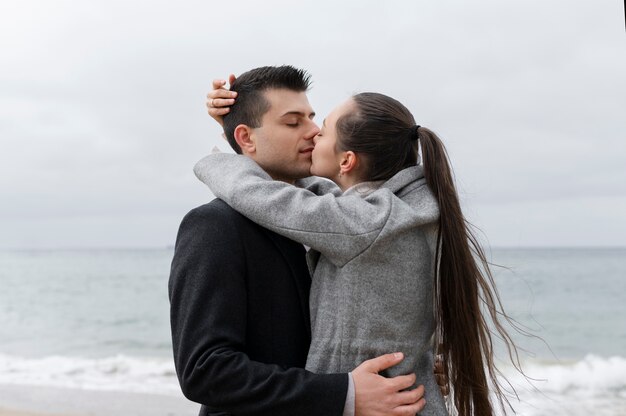 해변에서 키스하는 중간 샷 커플