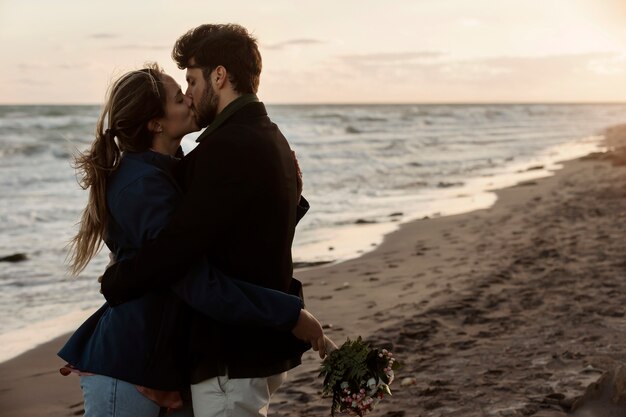 海辺でキスするミディアムショットのカップル