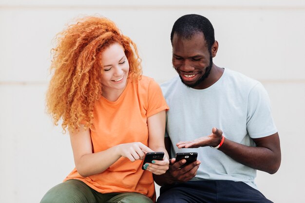 Medium shot of couple laughing at the phones