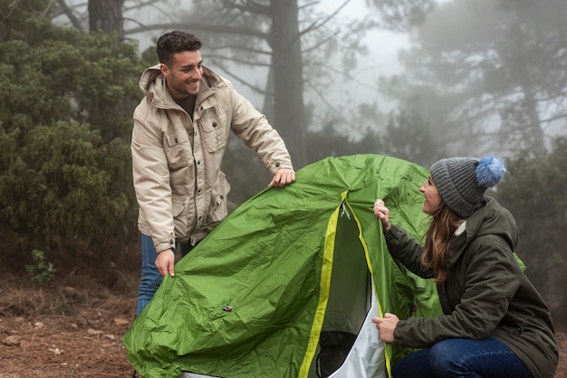 Medium shot couple putting up a tent