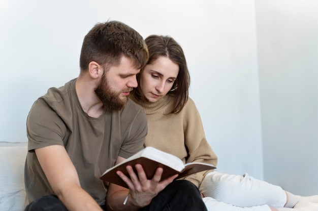 Пара среднего плана читает библию вместе