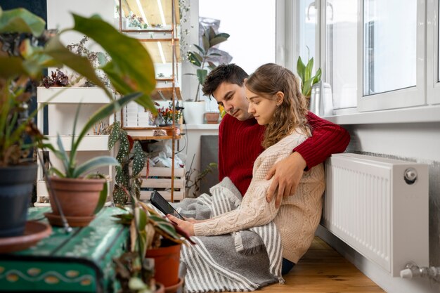 Medium shot couple sitting near heater