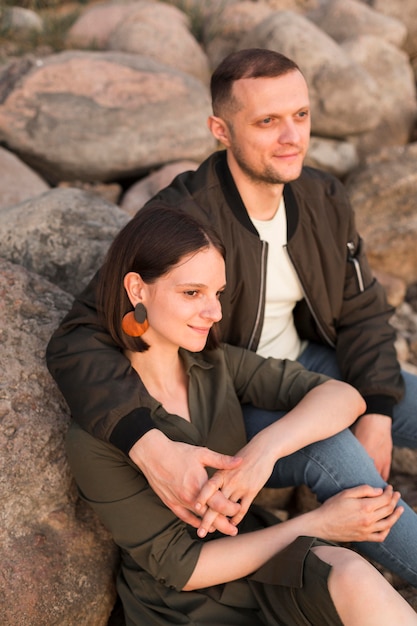 Medium shot couple sitting on rocks