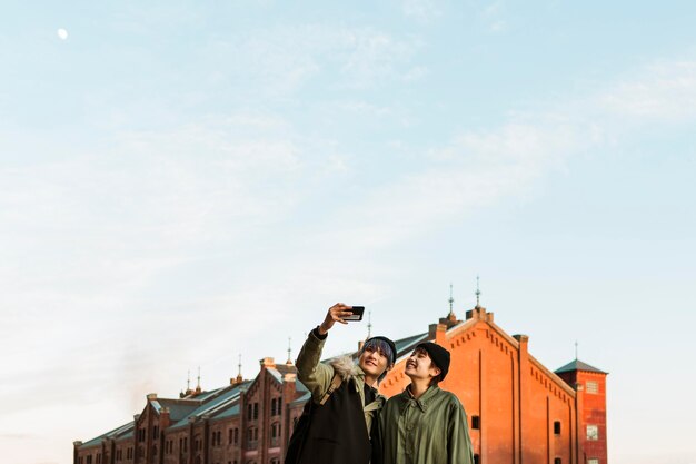 Free photo medium shot couple taking selfie outdoors