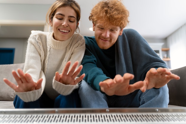 Medium shot couple warming up with heater