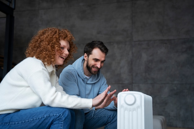 Free photo medium shot couple warming up with heater