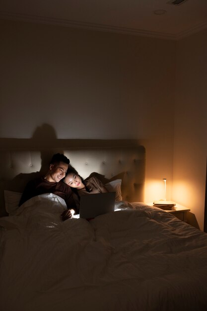 ベッドで映画を見ているミディアムショットのカップル
