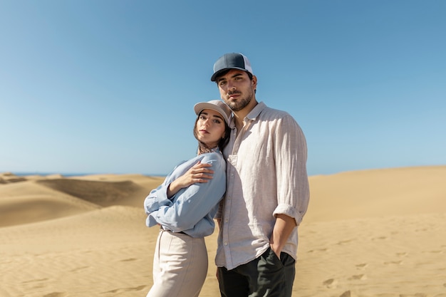 Medium shot couple wearing trucker hats in desert