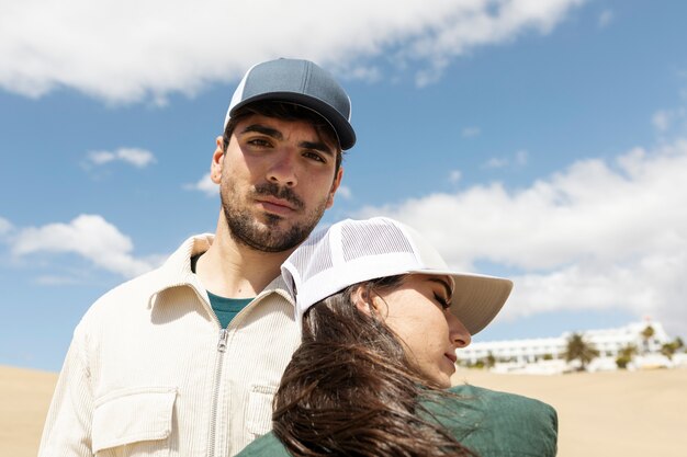 Medium shot couple wearing trucker hats in desert