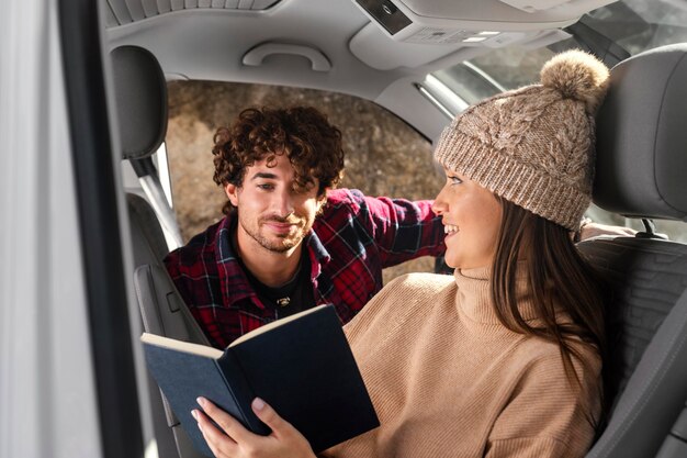 Medium shot couple with book in car