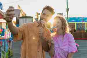 Free photo medium shot couple with lollipops taking a selfie