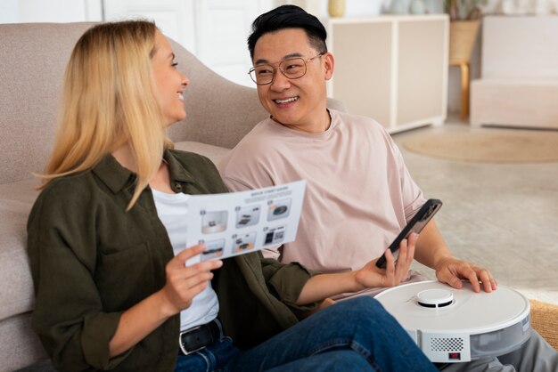 Free photo medium shot couple with robotic vacuum cleaner at home