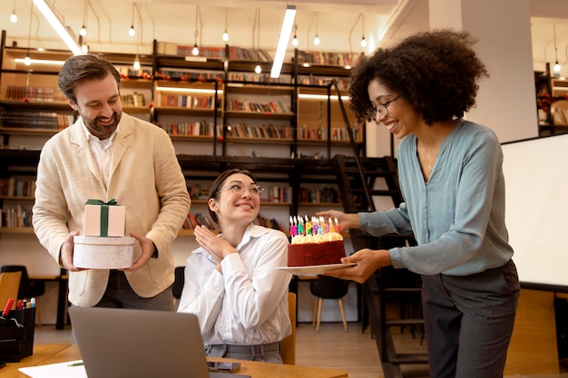 Medium shot coworkers celebrating with cake