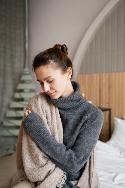 Medium shot cozy woman using blanket