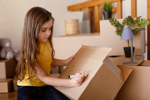 Free photo medium shot cute girl writing on box