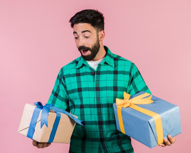 Средний снимок восхищенный парень держит подарки
