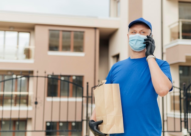 Free photo medium shot delivery man holding bag