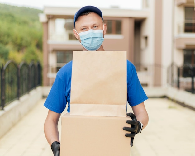 Free photo medium shot delivery man wearing mask