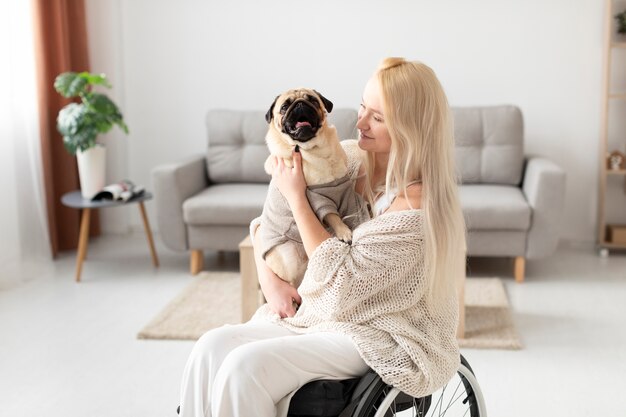 かわいい犬を保持しているミディアムショット障害者の女性