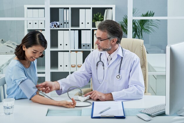 Medium shot of doctor checking blood pressure of female patient