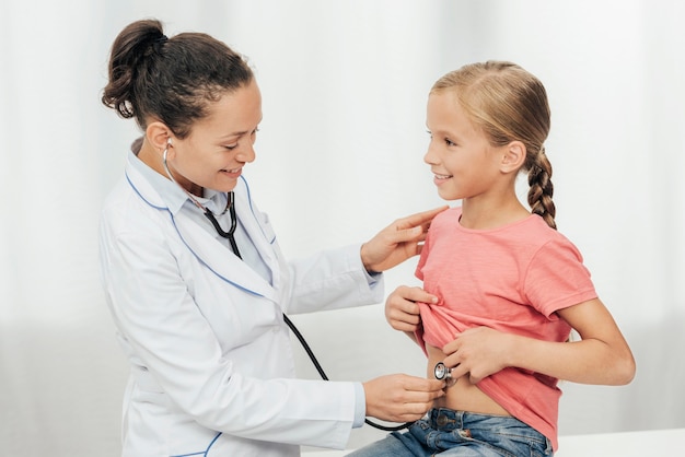 Medium shot doctor checking girl's abdomen