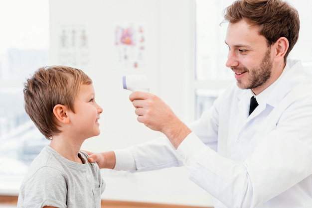 Medium shot doctor checking kid temperature