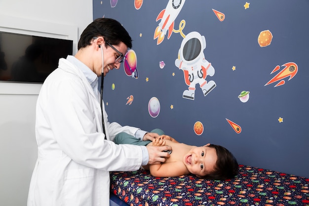 Medium shot doctor examining smiley baby