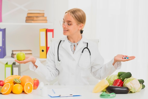 Medium shot doctor holding up and apple and pills