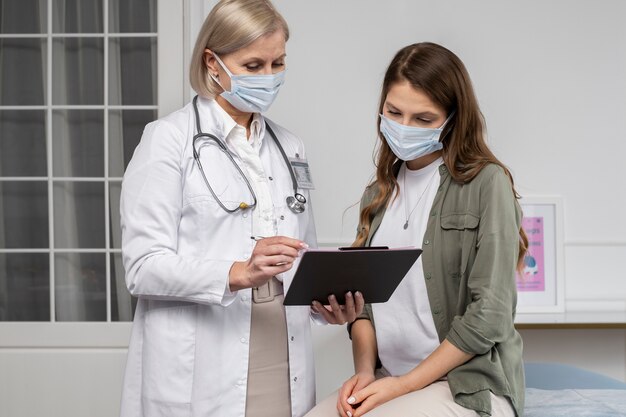 Medium shot doctor and patient wearing masks