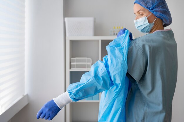 Medium shot doctor putting on medical gown