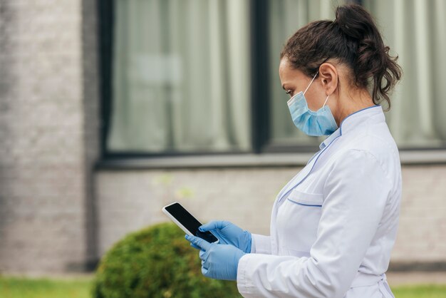 Foto gratuita medico del colpo medio che manda un sms con il telefono