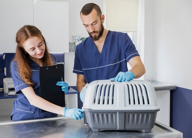 Medium shot doctors with clipboard and cat cage