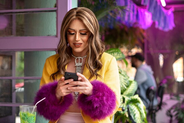 Medium shot drag queen holding smartphone